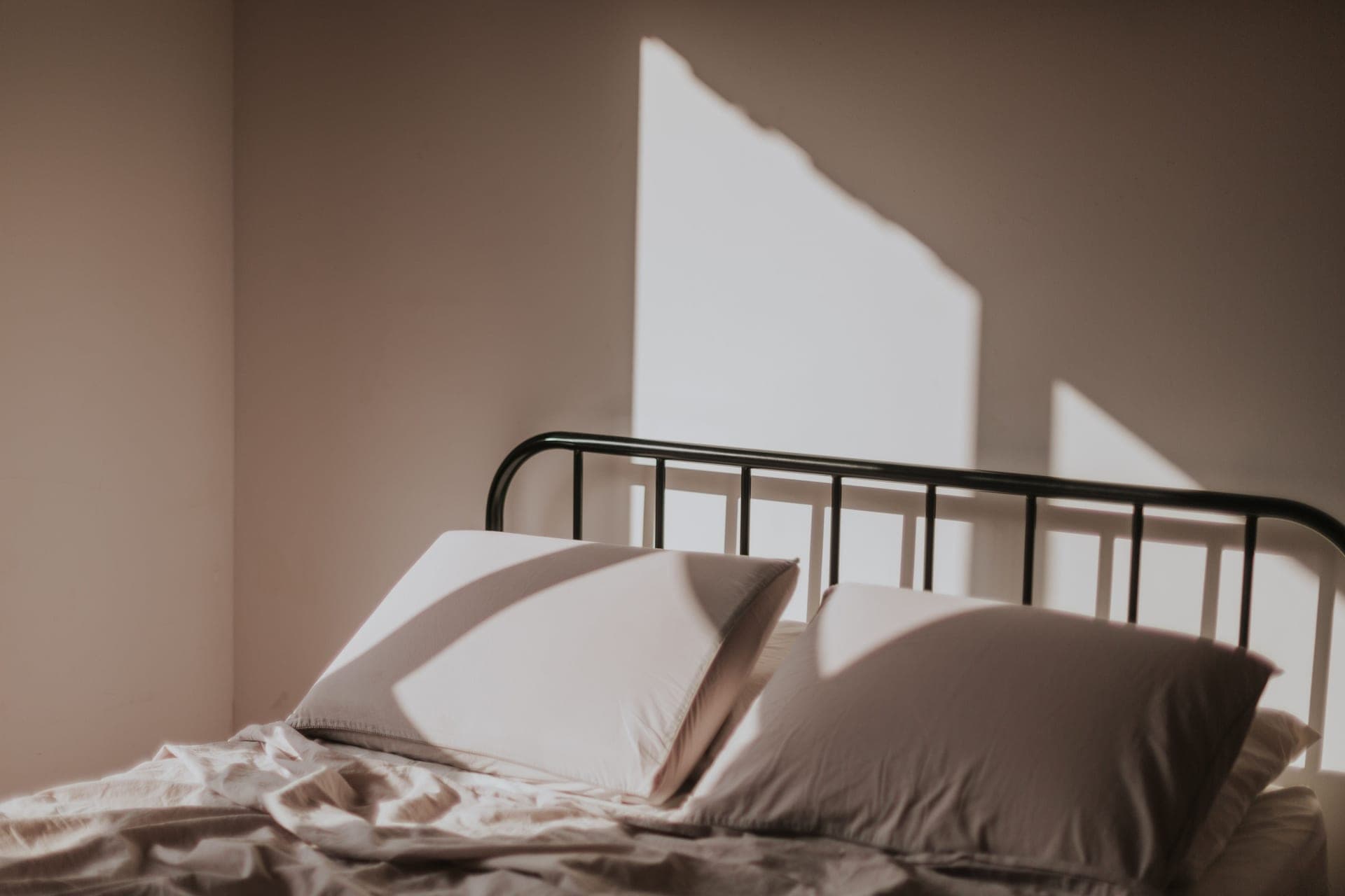 A neatly made bed with layered linen in warm morning light